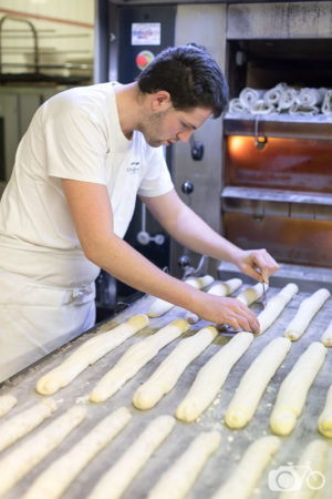 Boulanger scarifiant les baguettes tradition avant l'enfournement